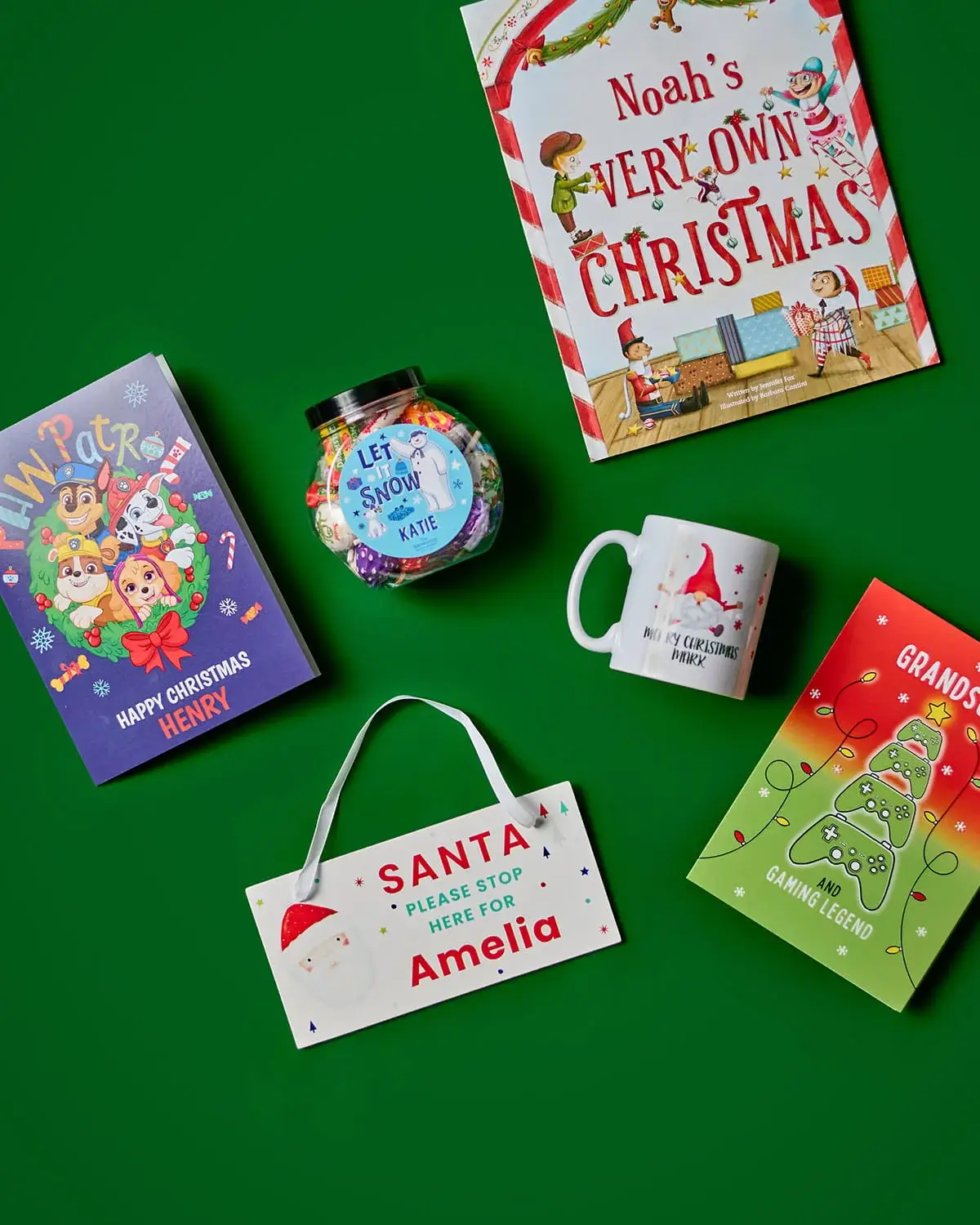 Personalised Christmas gift collection featuring festive cards, a children's Christmas book, a personalised mug, sweet jar, and Santa sign on a green background.